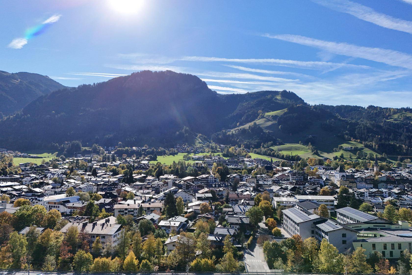 Weitläufiger Panoramablick auf eine malerische Stadt im Tal mit umliegenden grünen Bergen.