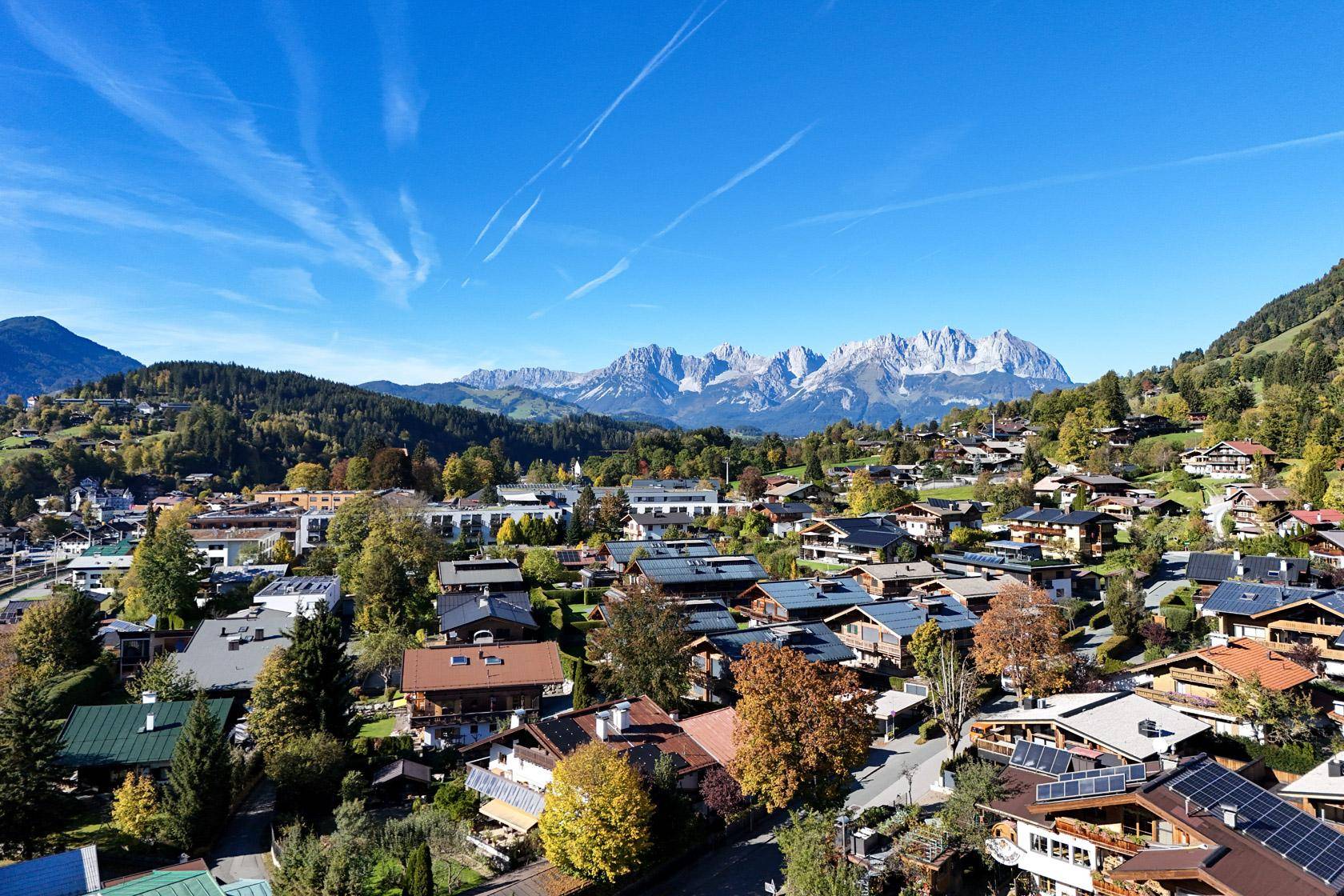 Malerische Ansicht einer Alpenstadt mit traditionellen Häusern und majestätischen Bergen im Hintergrund.