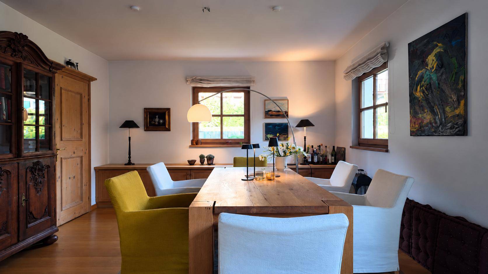 Eleganter Essbereich mit großem Holztisch, modernen Stühlen und einem antiken Holzschrank.