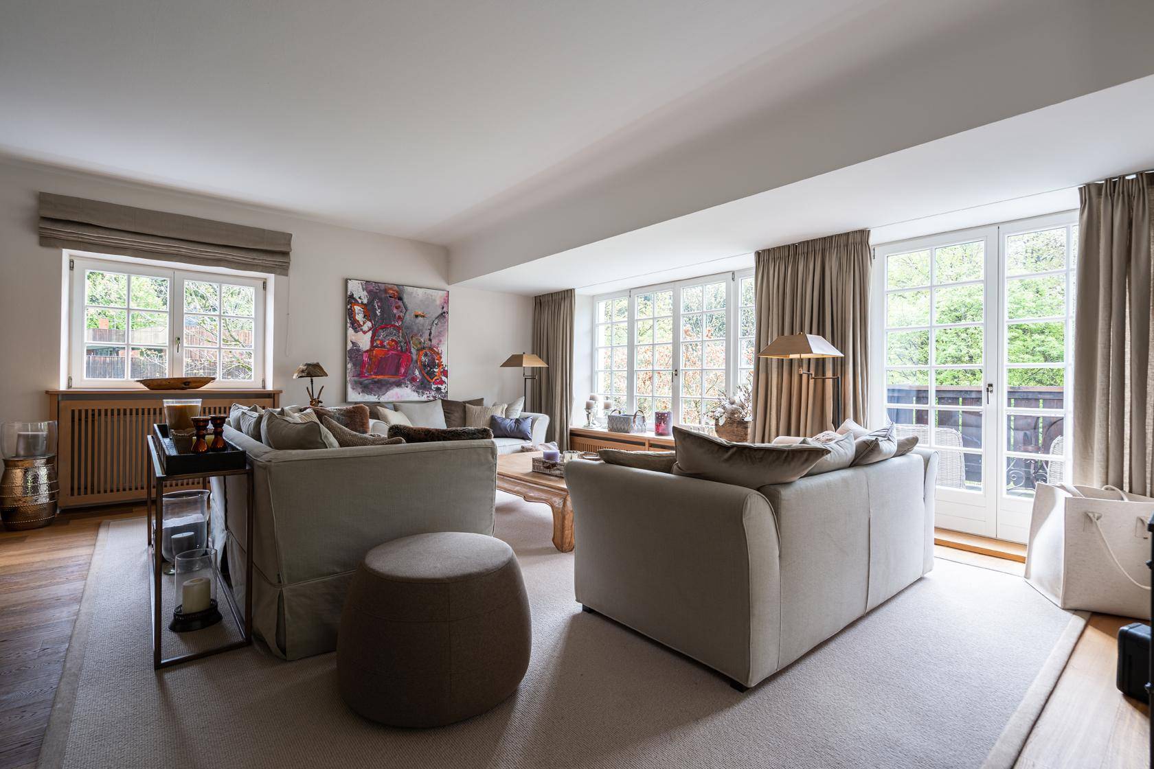 Helles Wohnzimmer mit großen Fenstern und Zugang zum Garten, ausgestattet mit komfortablen Sofas.