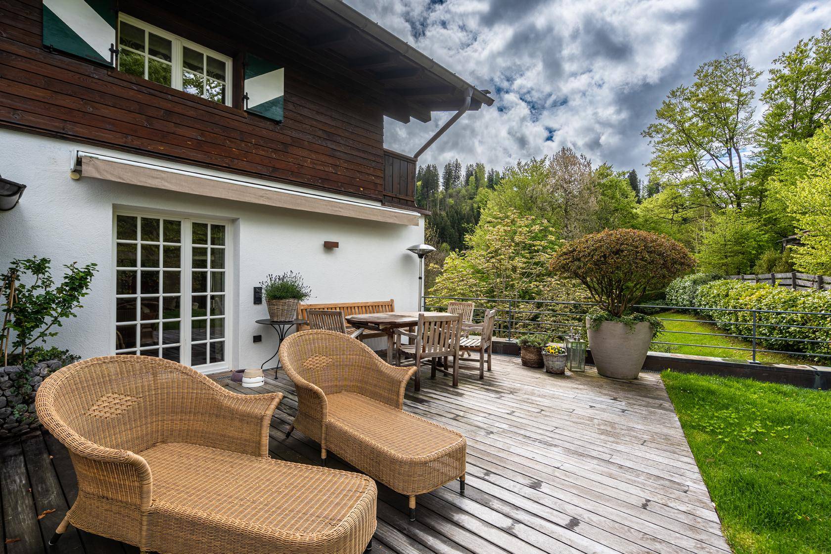 Geräumige Holzterrasse mit bequemen Liegestühlen und Essbereich, ideal für entspannte Stunden im Freien.