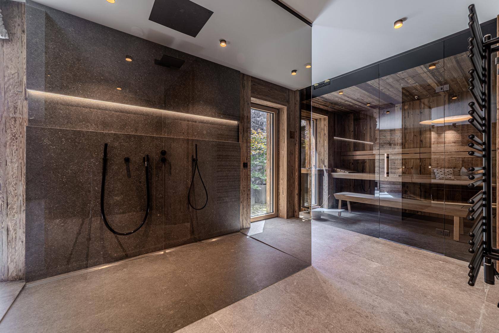 Modernes Badezimmer mit großer begehbarer Dusche und angrenzender Sauna für Wellnessmomente.