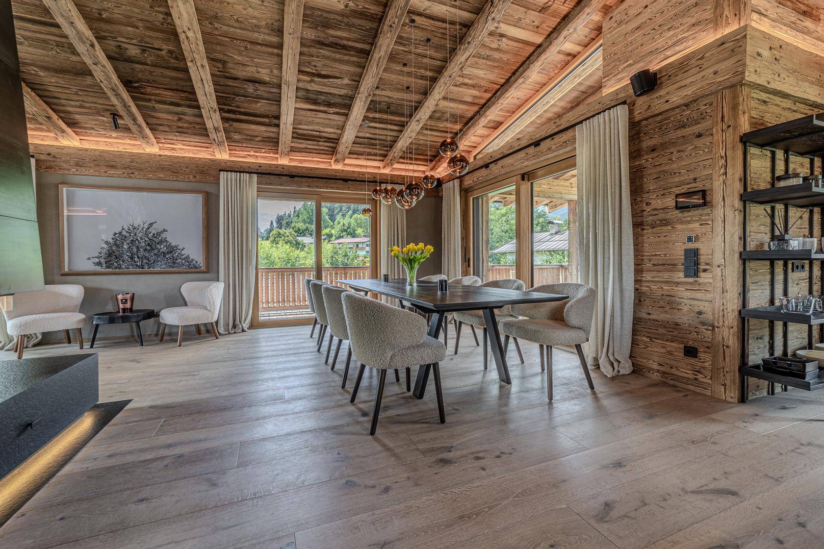 Eleganter Essbereich mit großem Holztisch, bequemen Stühlen und Zugang zum Balkon mit Bergblick.