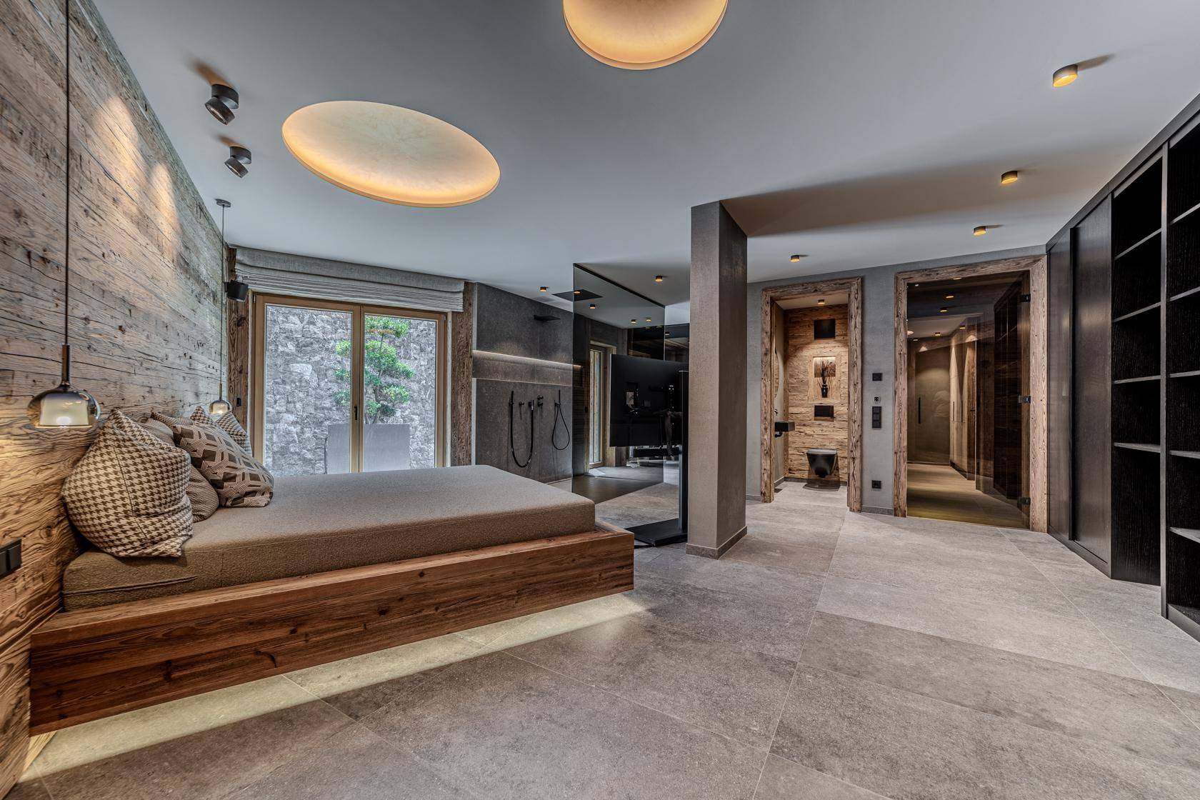 Geräumiges Schlafzimmer mit Holzbett, integriertem Badbereich und stilvoller Beleuchtung.