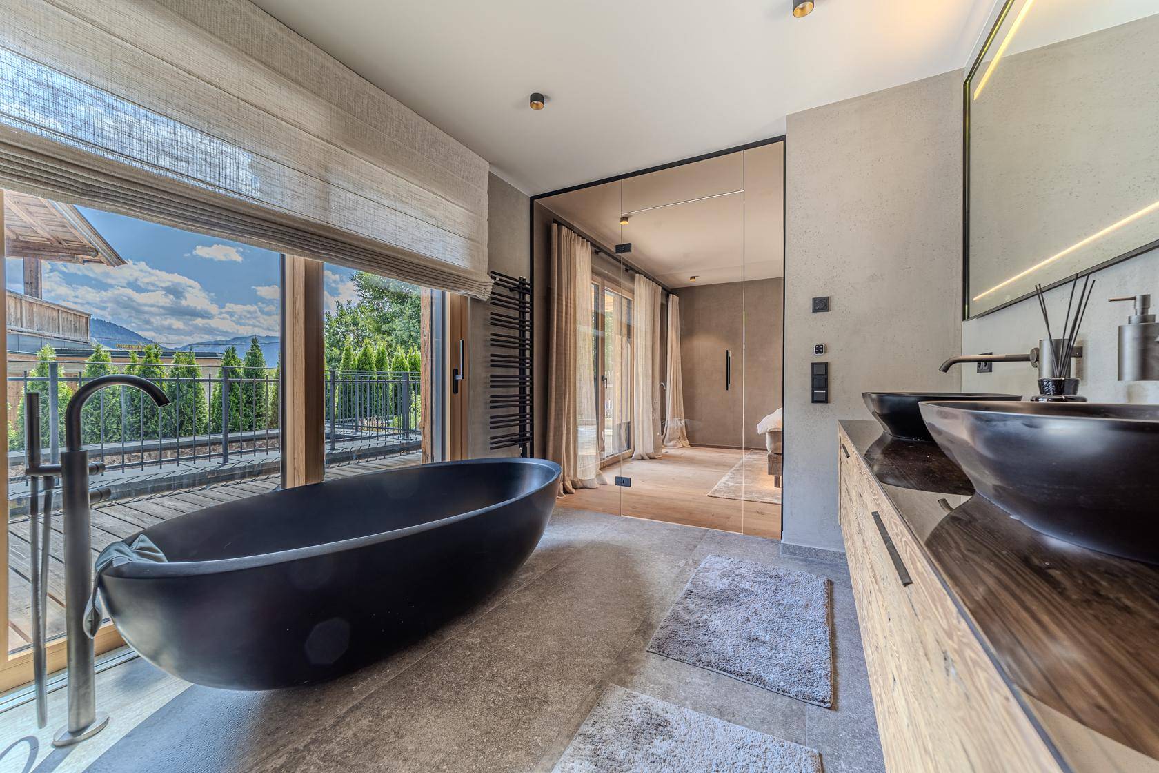 Luxuriöses Badezimmer mit freistehender Badewanne, Doppelwaschbecken und Zugang zu einem Außenbereich.