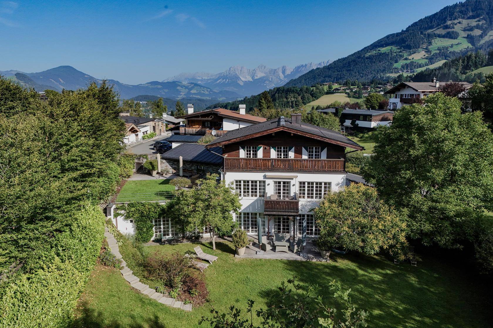 Panoramablick auf das Anwesen mit weitläufigem Garten und der beeindruckenden Berglandschaft im Hintergrund.