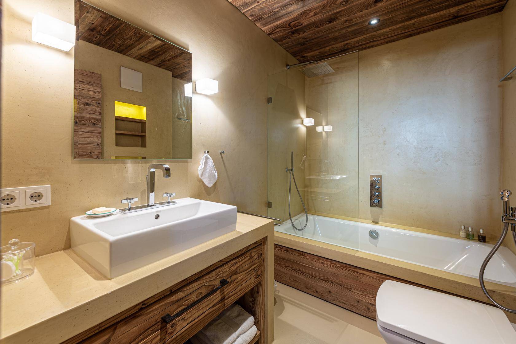Modernes Badezimmer mit Einzelwaschbecken, Badewanne mit Duschfunktion und Holzunterschrank.
