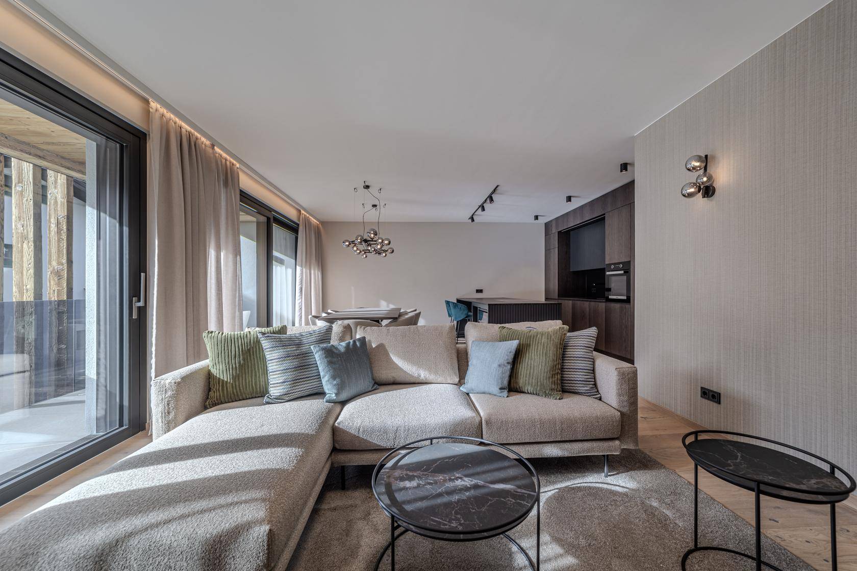 Helles Wohnzimmer mit bequemem Sofa, Holzboden und großen Schiebetüren zum Außenbereich.