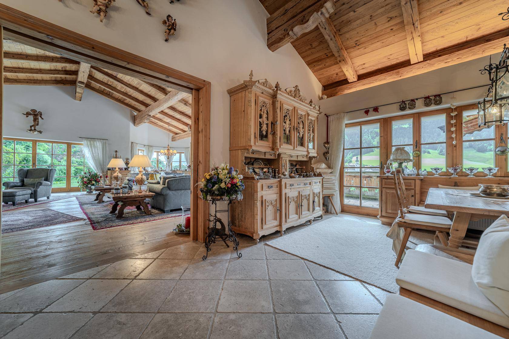 Traditioneller Essbereich mit Holzbüffet und Zugang zum hellen Wohnzimmer, umgeben von Natur.