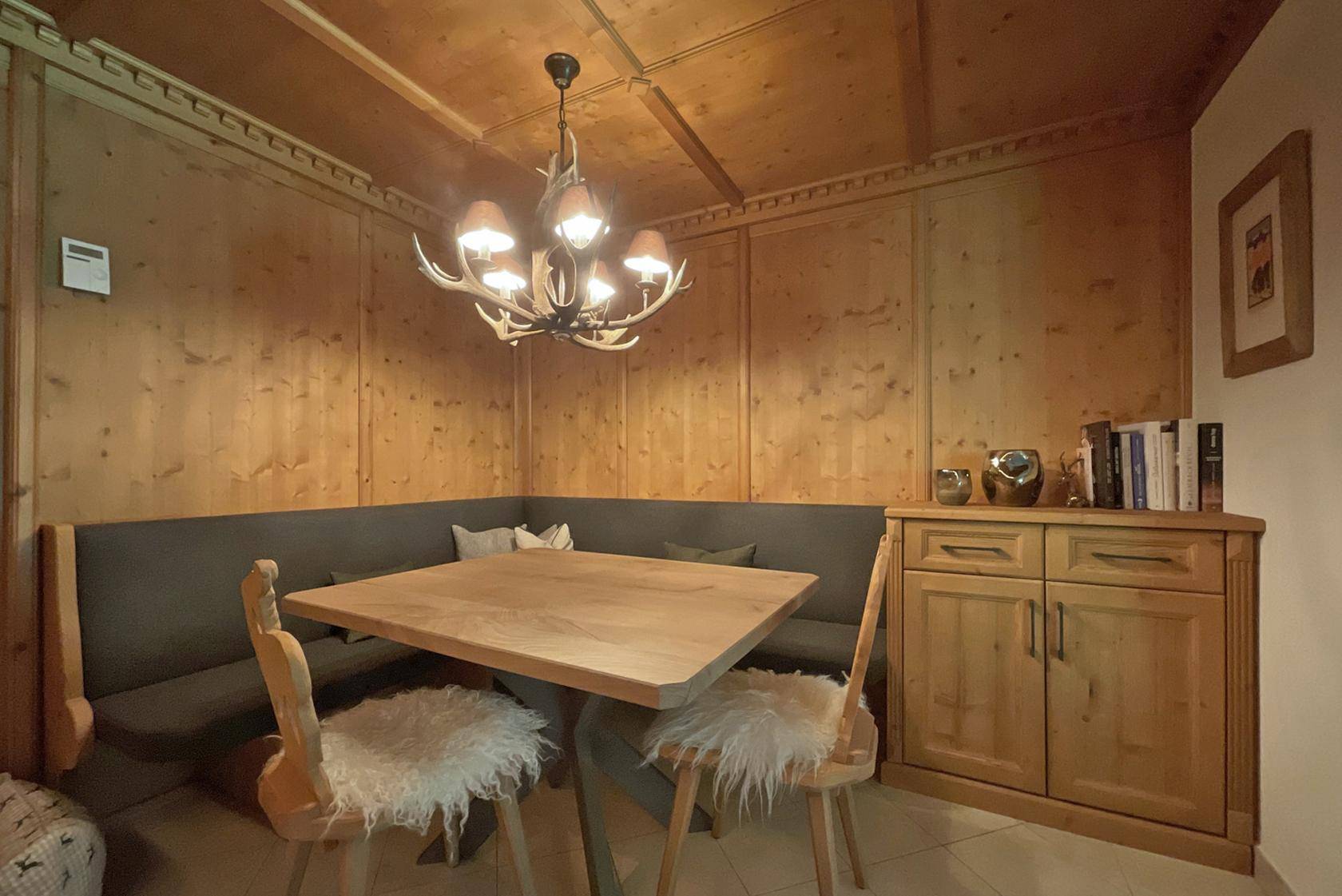 Traditioneller Essbereich mit Eckbank, Holztisch und Hirschgeweih-Kronleuchter.