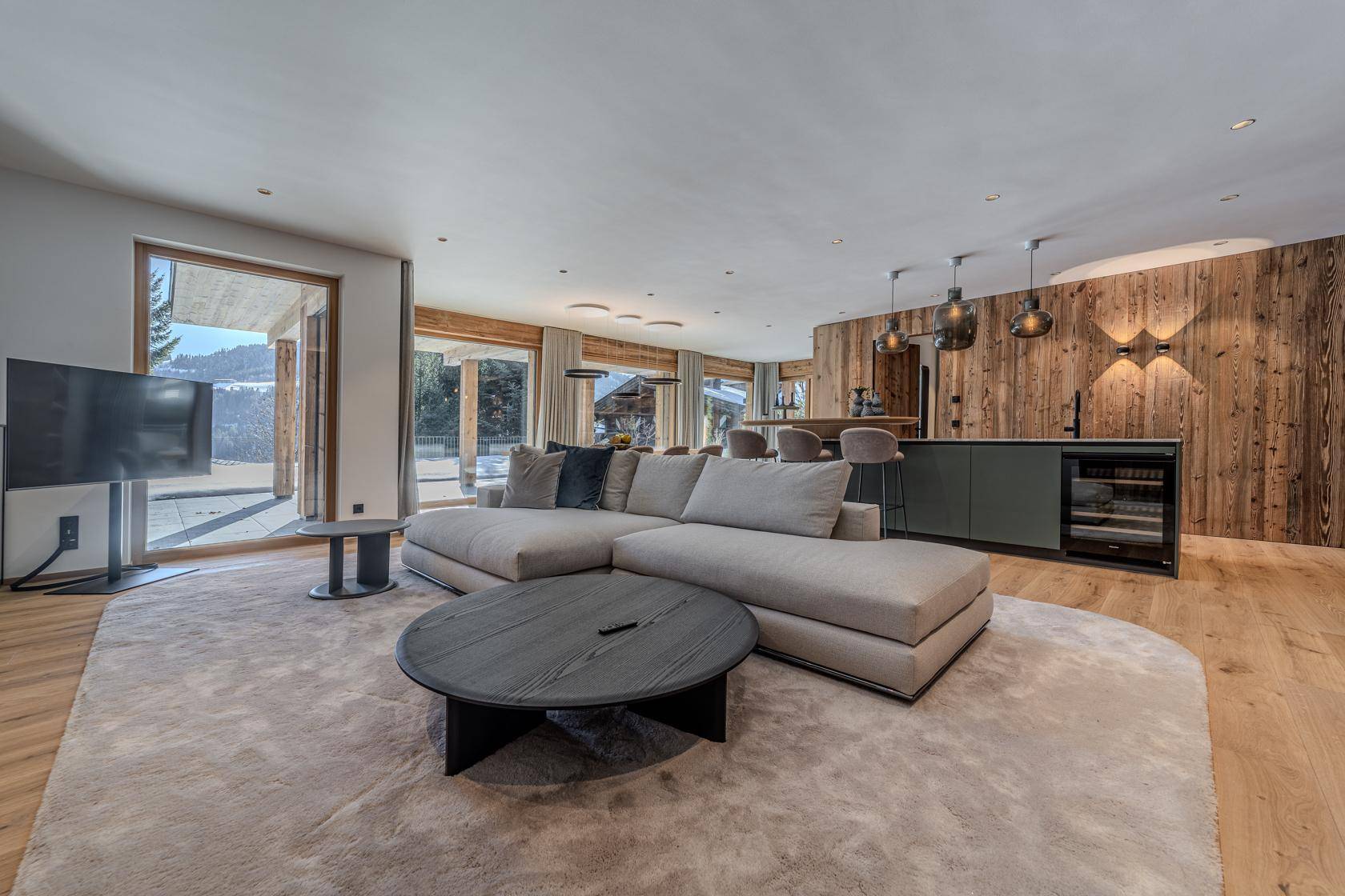 Gemütlicher Wohnbereich mit großem Sofa, Holzwänden und Zugang zur Terrasse.