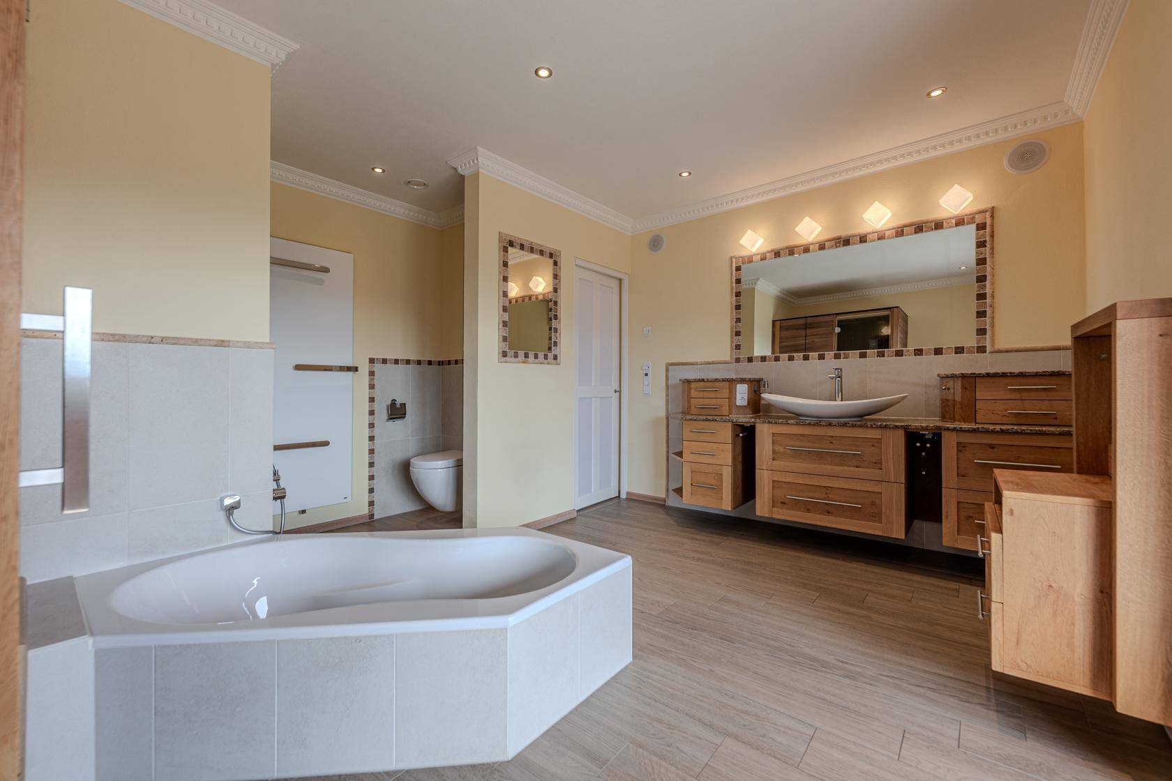 Elegantes Badezimmer mit Eckbadewanne, Doppelwaschbecken und modernen Armaturen.