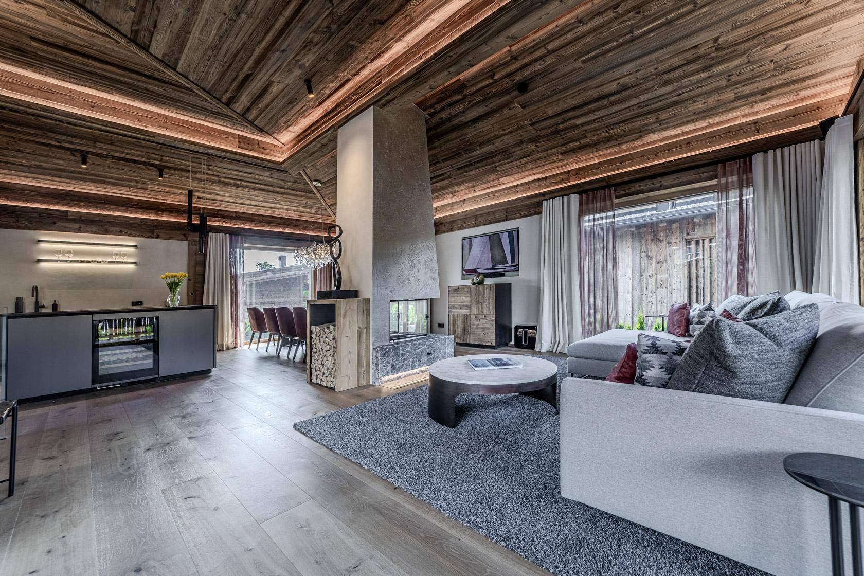 Heller Wohnbereich mit Kamin, bequemer Couch und integrierter Bar mit Weinkühler.