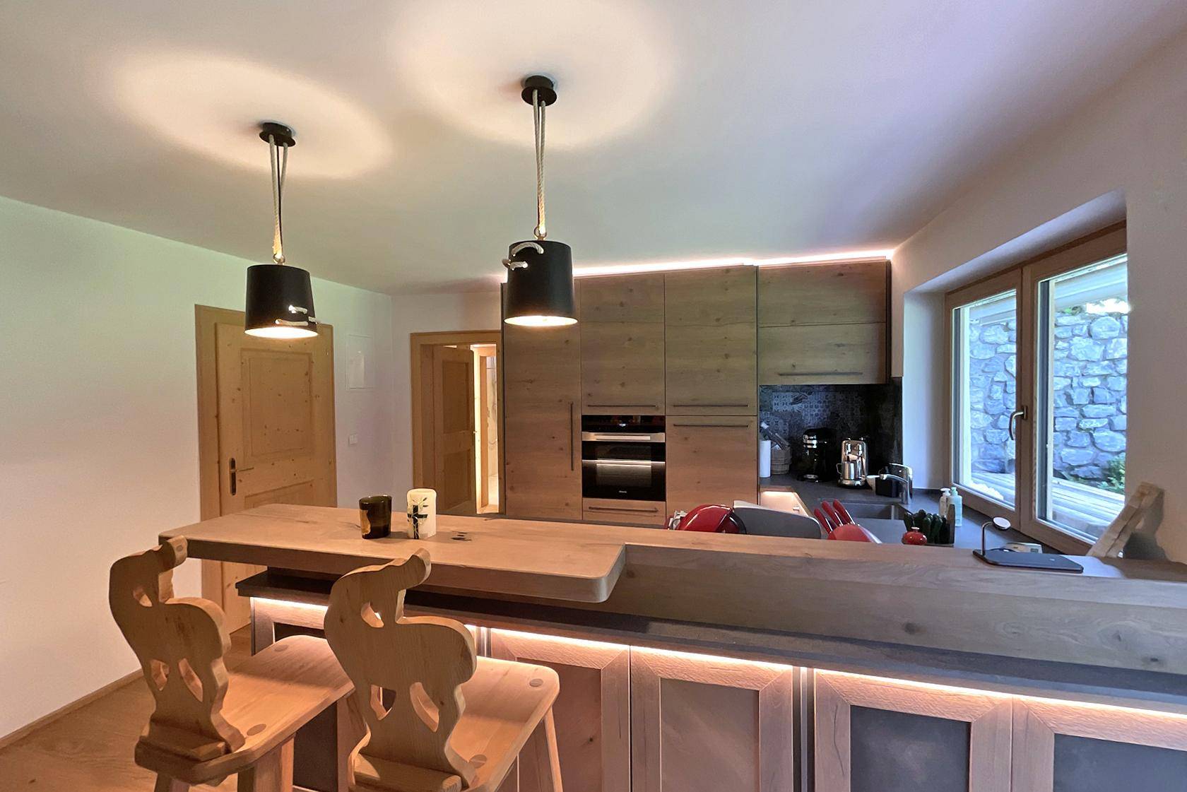 Offene Küche mit Holztheke, Barhockern und modernen Einbaugeräten.