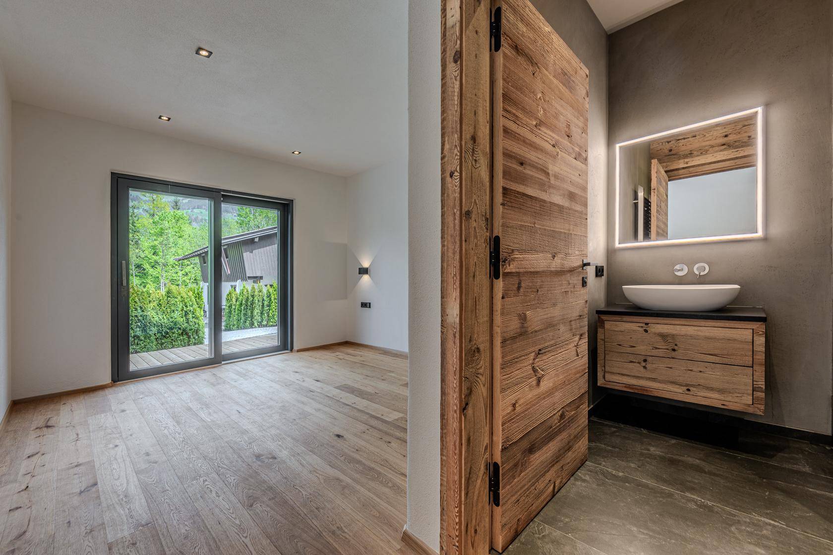 Helles Schlafzimmer mit Holzboden und angrenzendem modernen Badezimmer.
