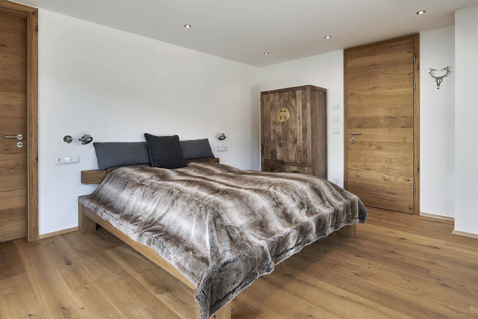 Gemütliches Schlafzimmer mit Holzboden, großem Bett und rustikalem Kleiderschrank.