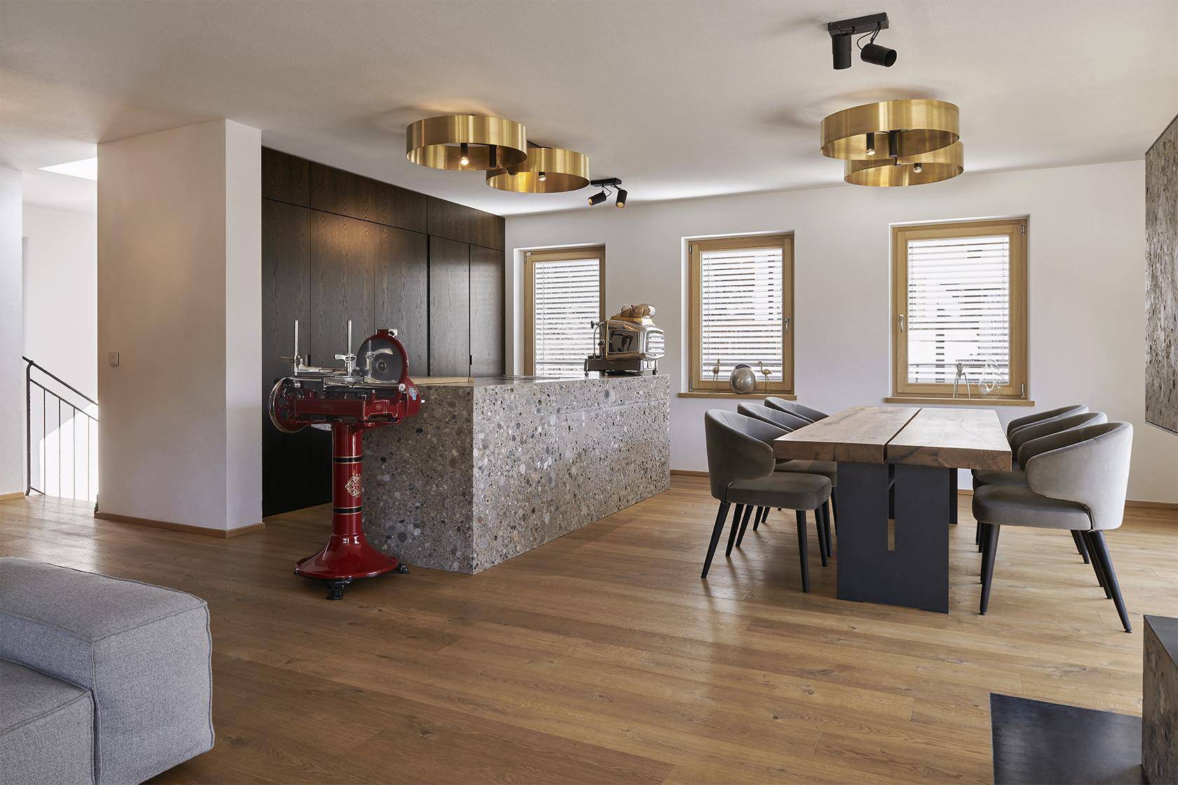 Heller Essbereich mit Holztisch, modernen Stühlen und einer Kücheninsel mit Steinoptik.