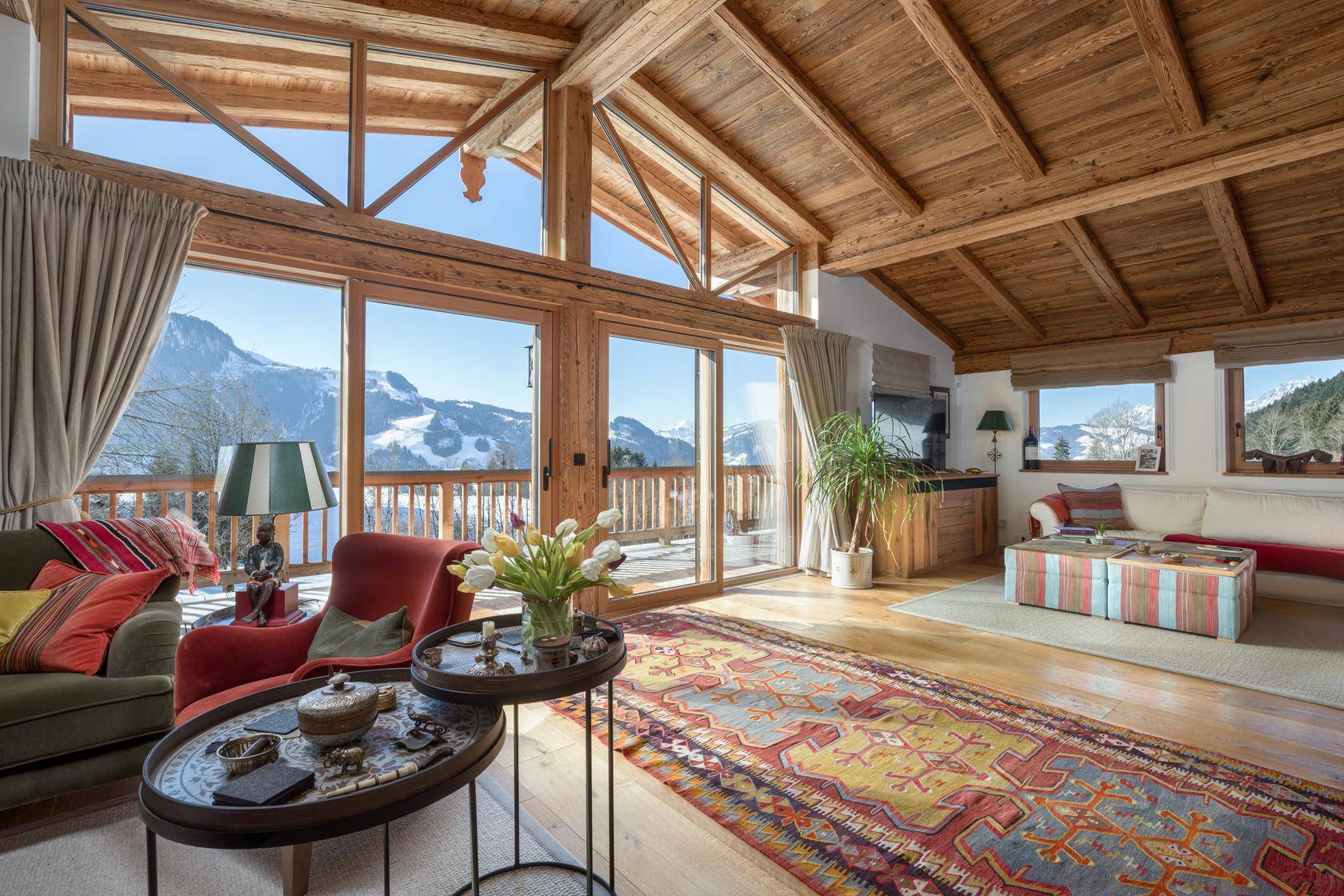 Helles Wohnzimmer mit großen Fenstern, Bergblick und rustikalen Holzelementen.