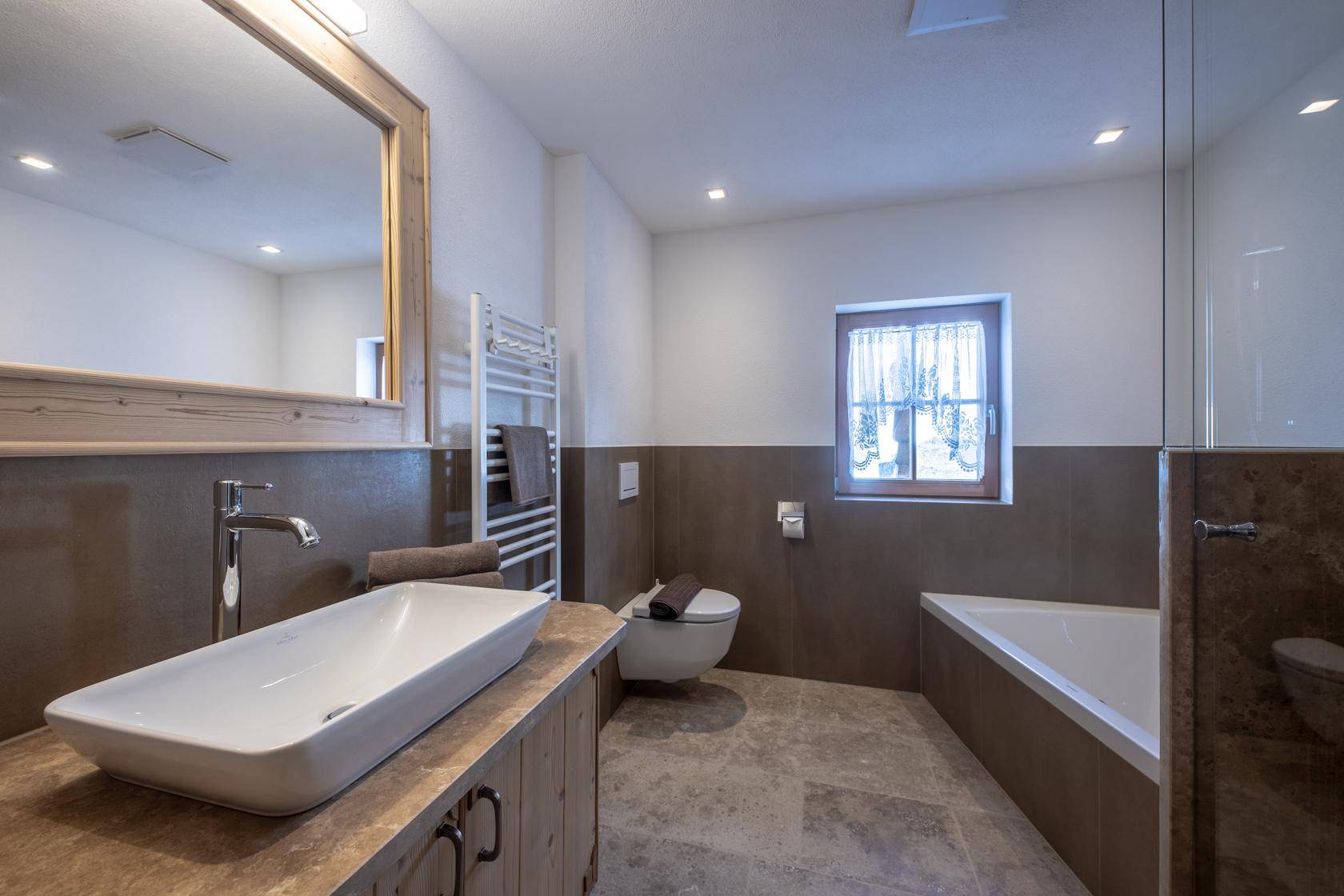 Modernes Badezimmer mit Badewanne, Waschbecken und beheiztem Handtuchhalter.