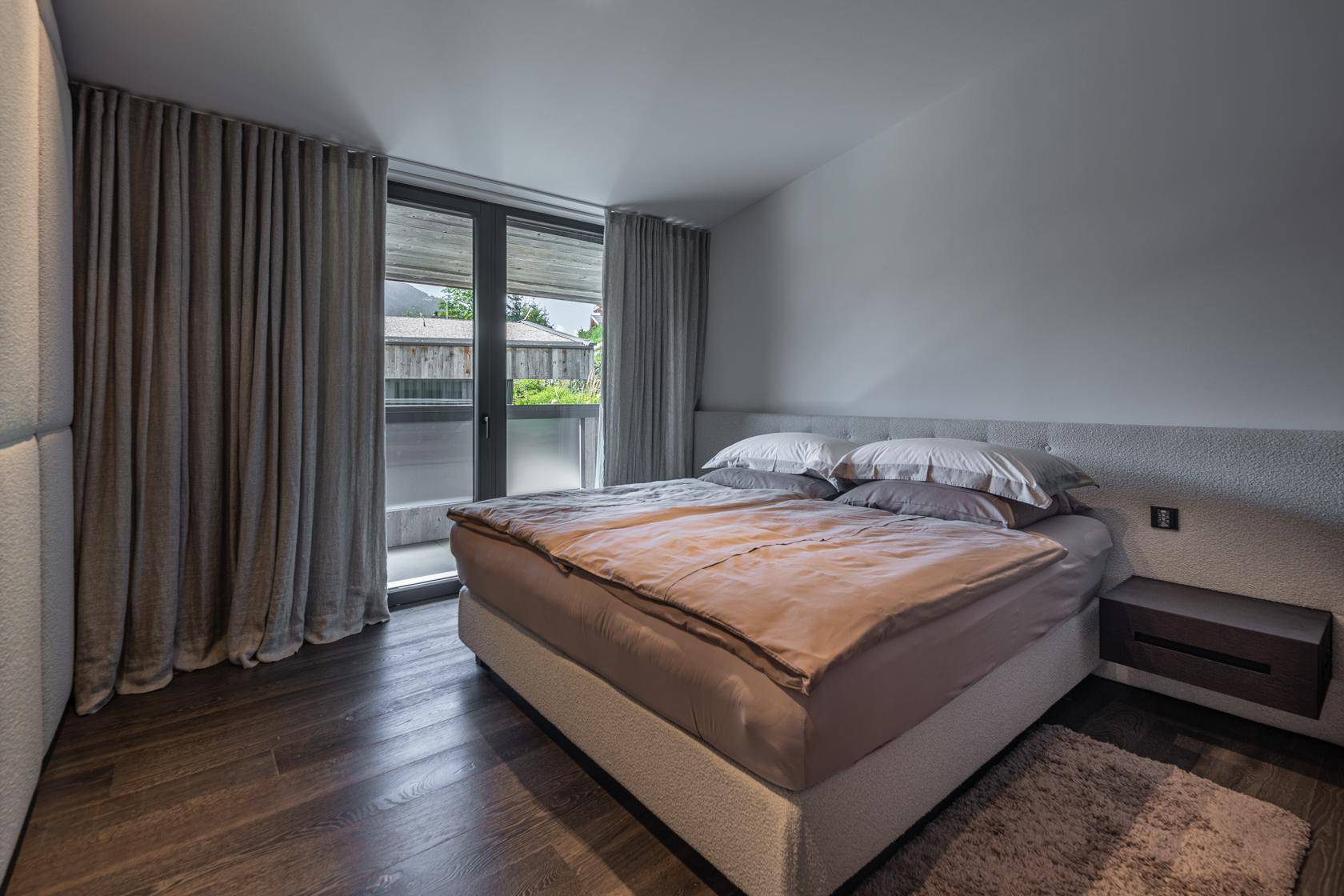 Gemütliches Schlafzimmer mit großem Bett, Holzboden und direktem Zugang zu einem Außenbereich.
