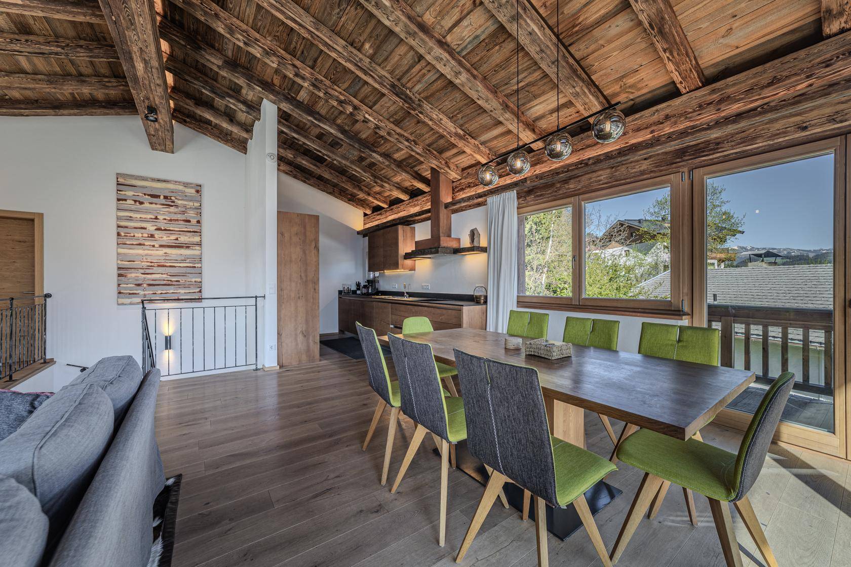 Moderne Küche mit Holzelementen, Essbereich und Blick ins Grüne.