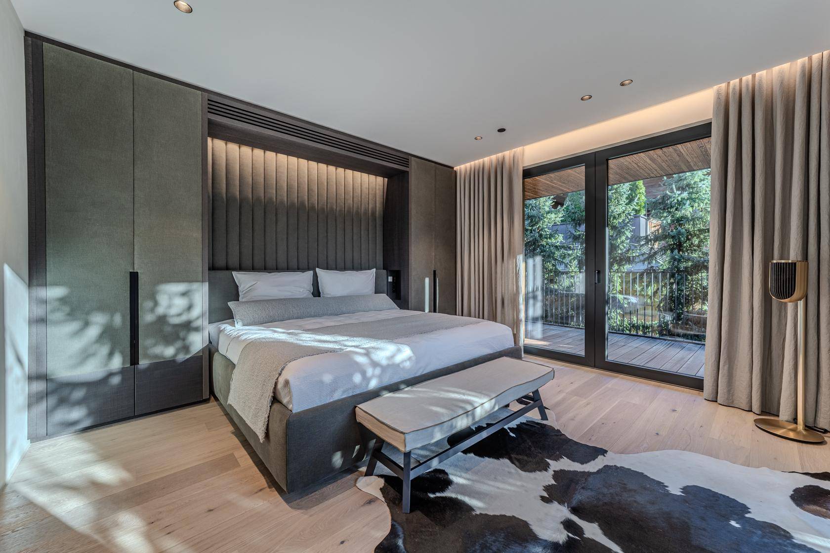 Stilvolles Schlafzimmer mit grauen Einbauschränken, gepolstertem Bett und Balkonzugang.