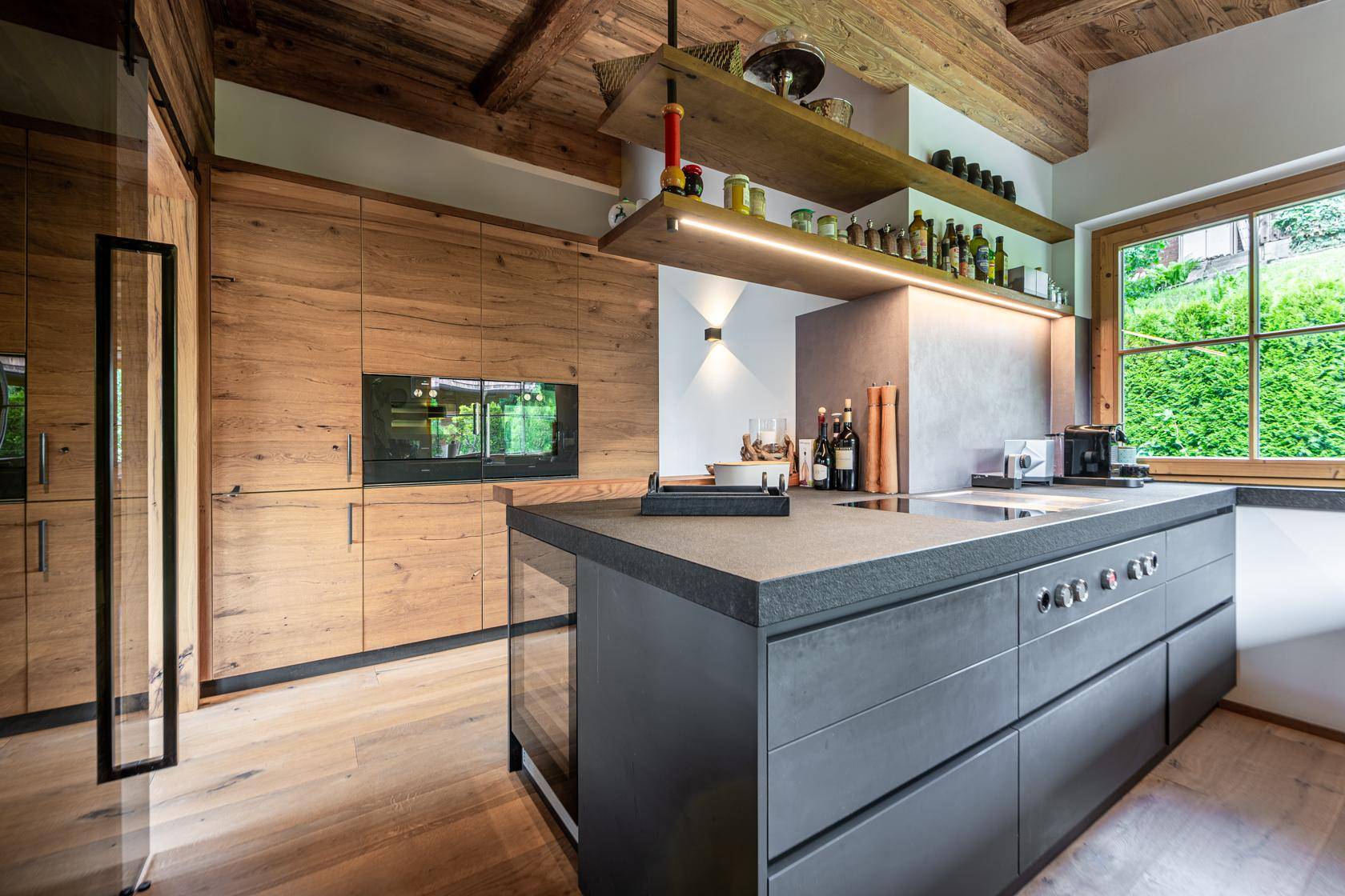 Moderne Küche mit Holzfronten, dunkler Kücheninsel und integrierten Geräten, hell und funktional.