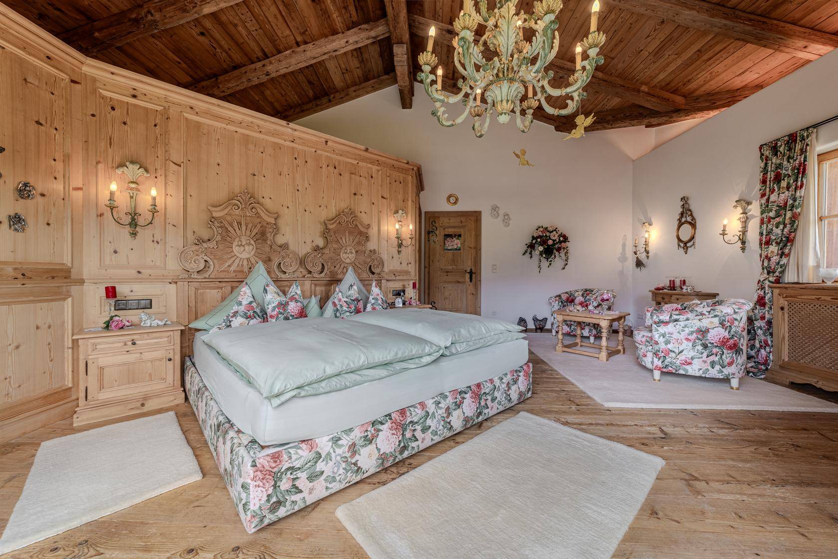 Traditionelles Schlafzimmer mit Holzbett, Holzvertäfelung und floralen Akzenten unter einer Holzbalkendecke.