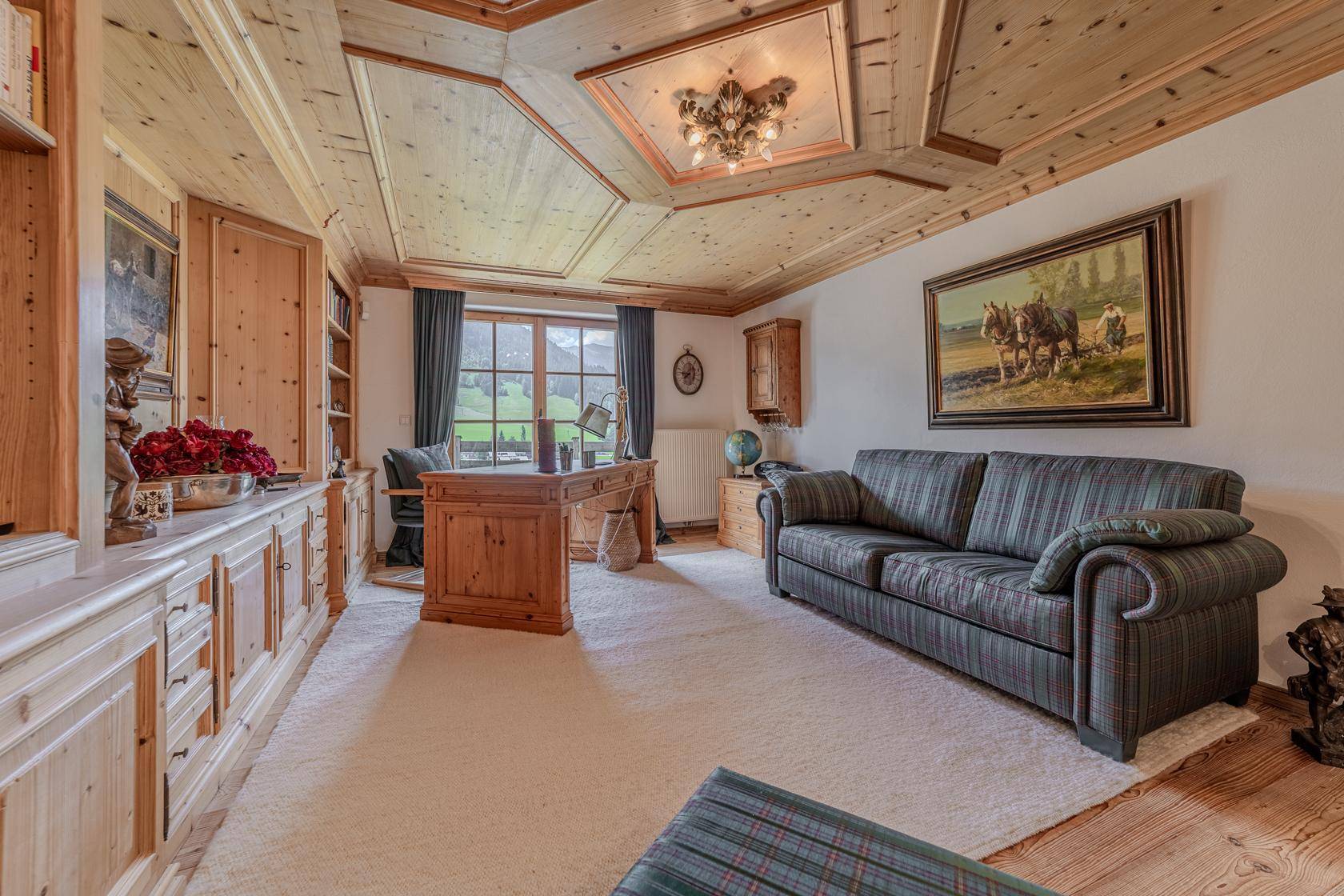 Elegantes Büro mit Holzvertäfelung, Einbauschränken und Blick auf die Berglandschaft.
