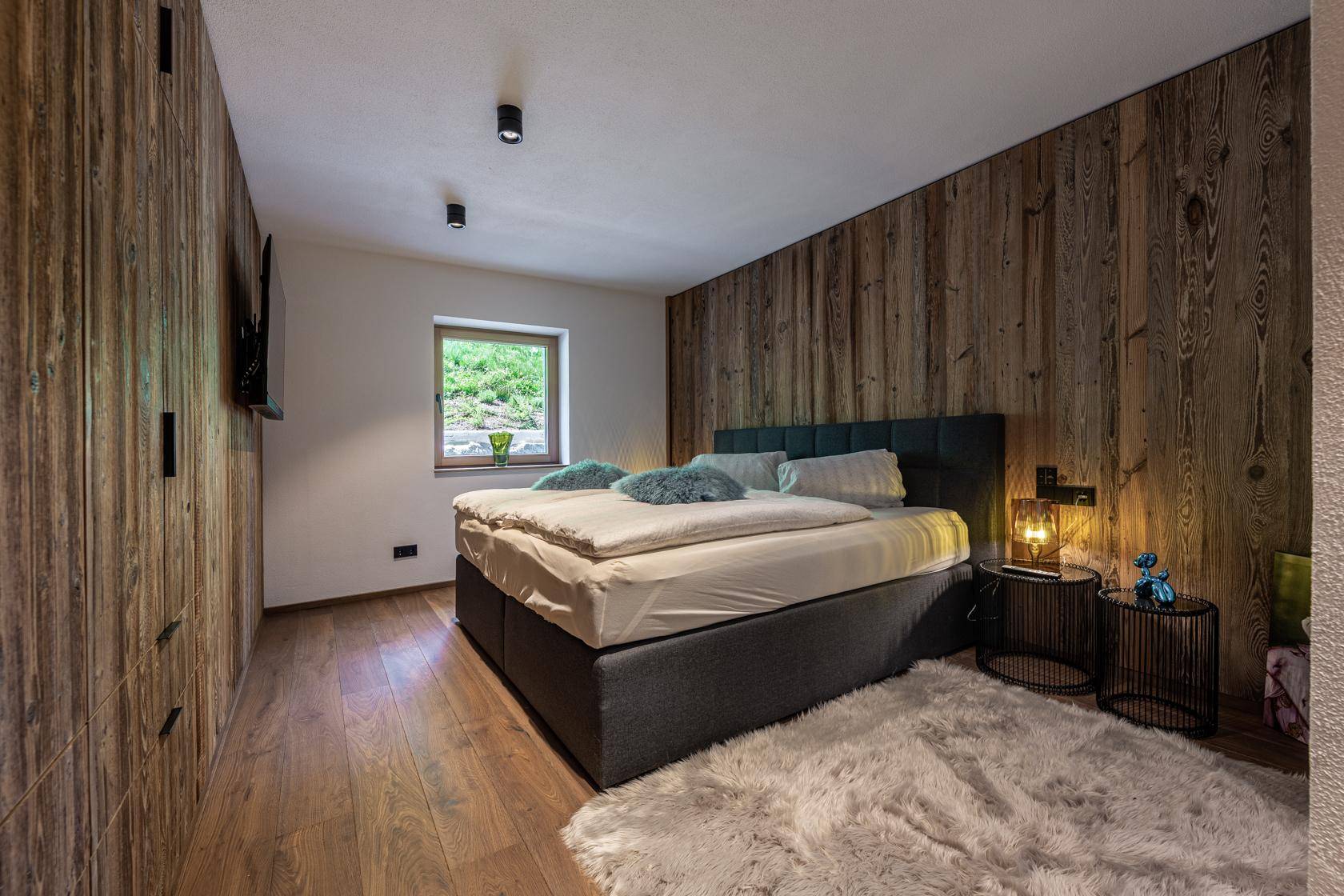 Gemütliches Schlafzimmer mit Holzwänden, Doppelbett und flauschigem Teppich.