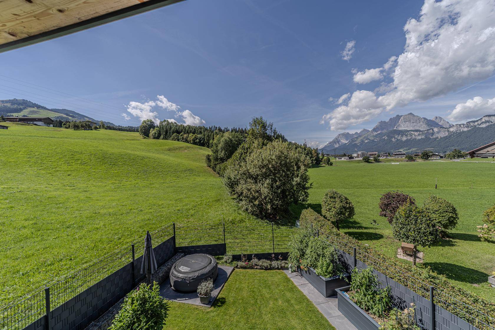 Großer Garten mit Whirlpool und weitem Blick auf die umliegende grüne Landschaft und Berge.