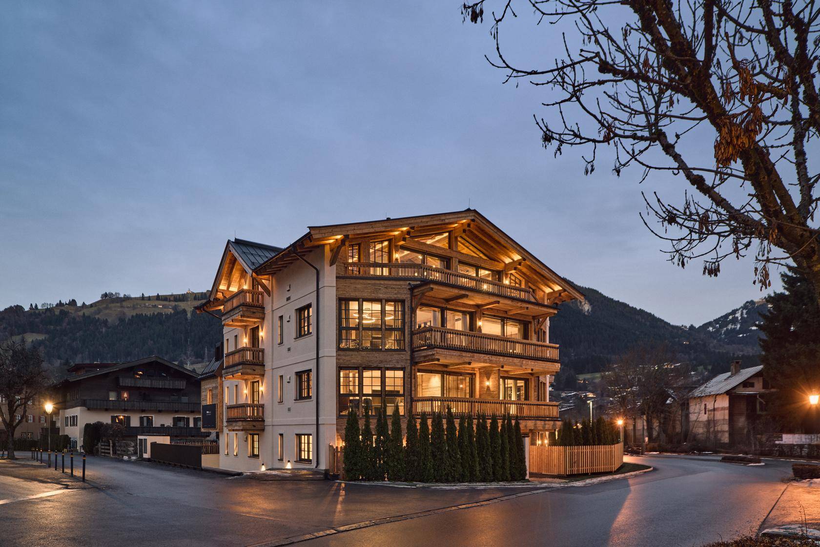 Attraktives Mehrfamilienhaus im alpinen Stil mit Holzbalkonen und moderner Architektur in den Bergen.
