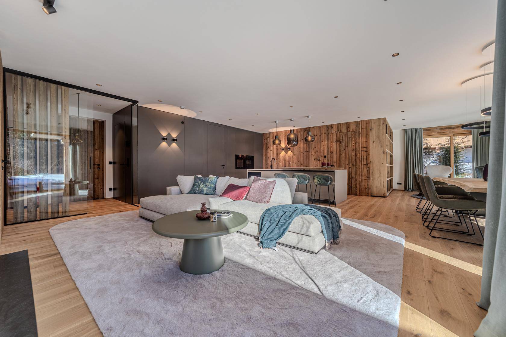 Heller, offener Wohnbereich mit Holzwänden, bequemer Couch und Zugang zur Terrasse.