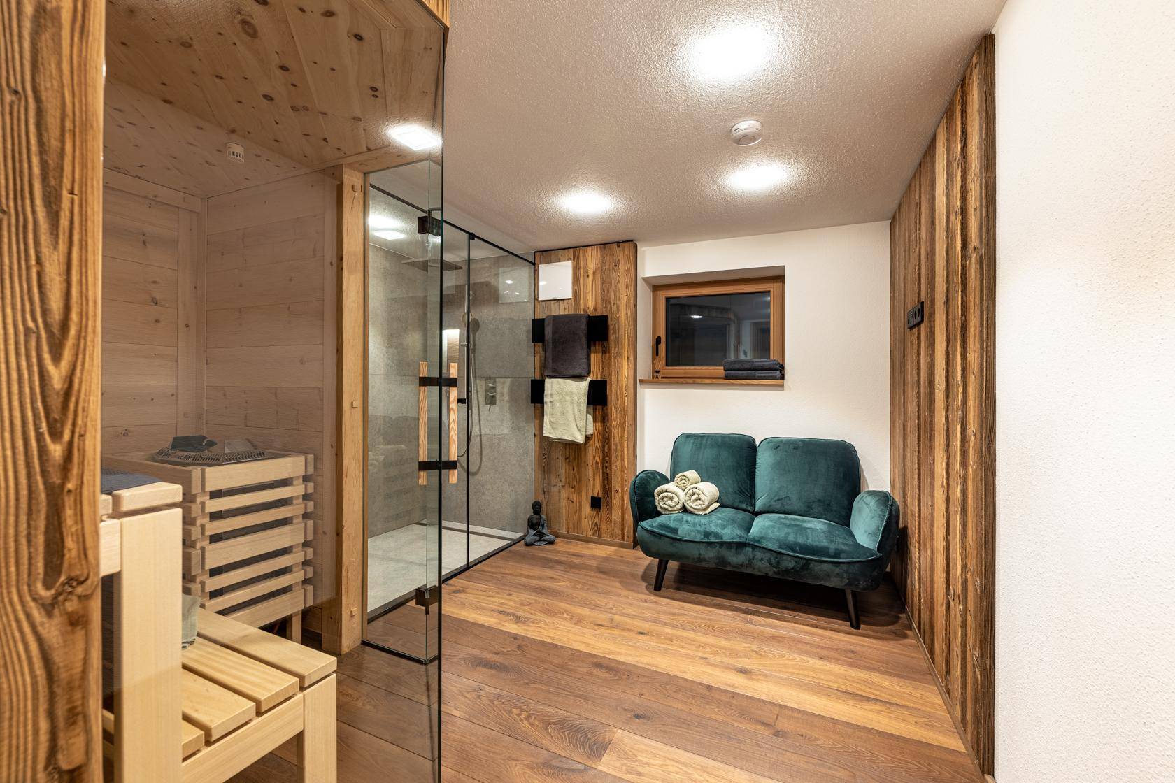 Entspannender Wellnessbereich mit Sauna, Dusche und Sitzgelegenheit.
