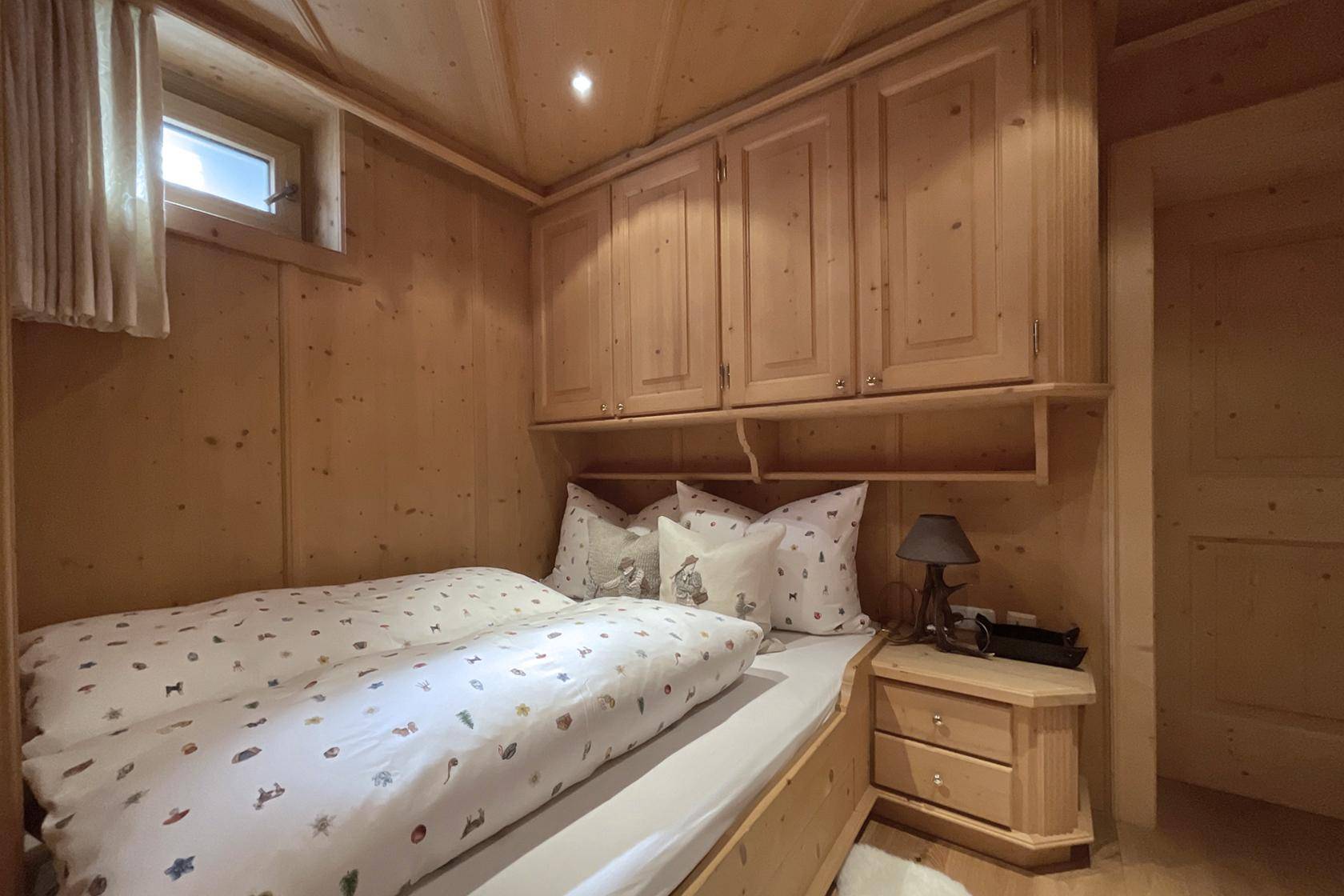 Kleines Schlafzimmer mit Holztäfelung, Einzelbett und praktischen Einbauschränken.