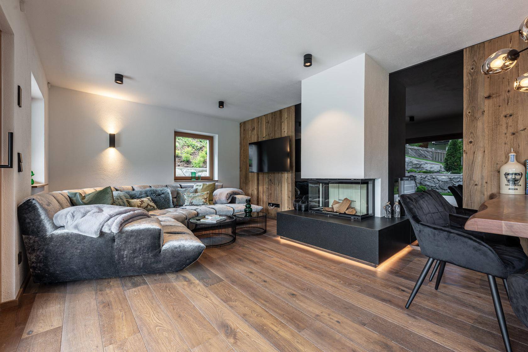 Gemütliches Wohnzimmer mit großem Ecksofa, modernem Kamin und Holzboden.