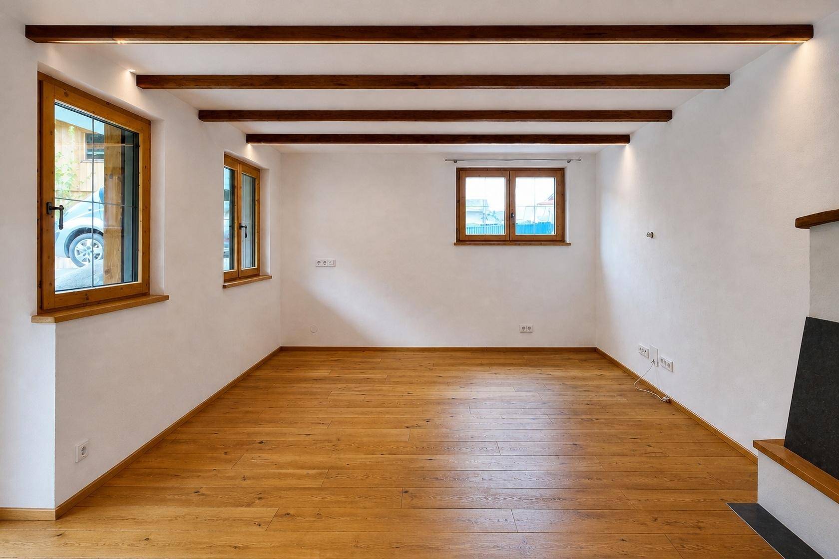 Heller Wohnraum mit Holzbalken und Parkettboden, gut beleuchtet durch mehrere Fenster, bietet viel Platz.