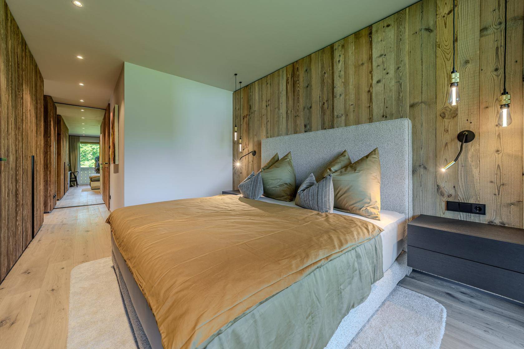 Gemütliches Schlafzimmer mit Holzwand, Doppelbett und integrierten Schränken.