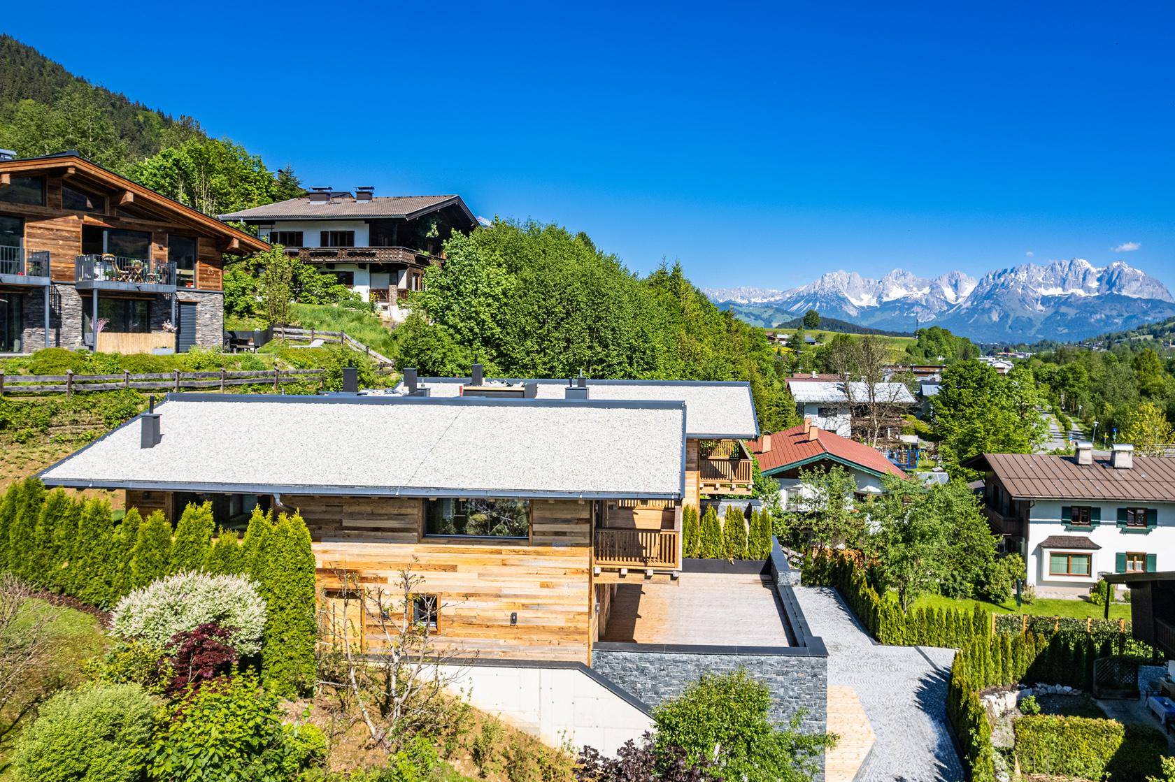 Panoramablick auf die luxuriösen Chalets in alpiner Landschaft mit schneebedeckten Bergen im Hintergrund.