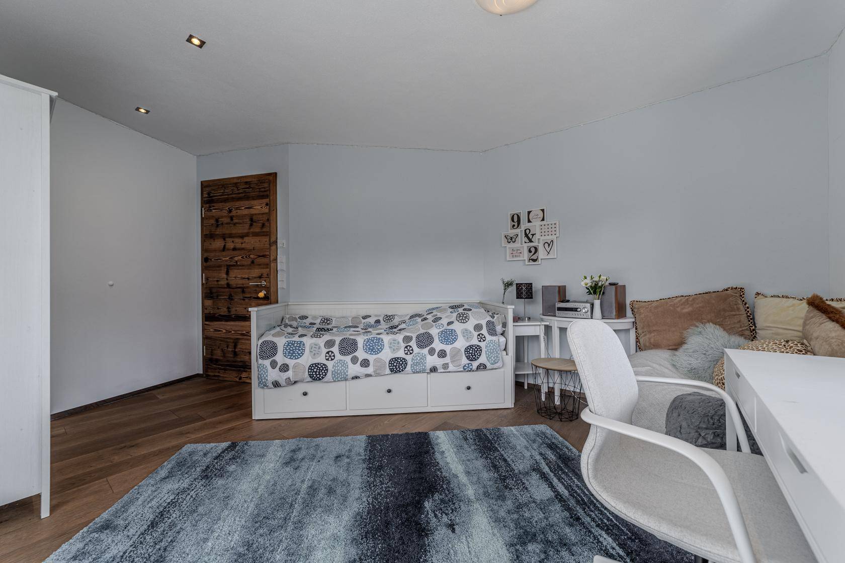 Helles Schlafzimmer mit Tagesbett, Schreibtisch und Holzboden, ideal als Gäste- oder Kinderzimmer.