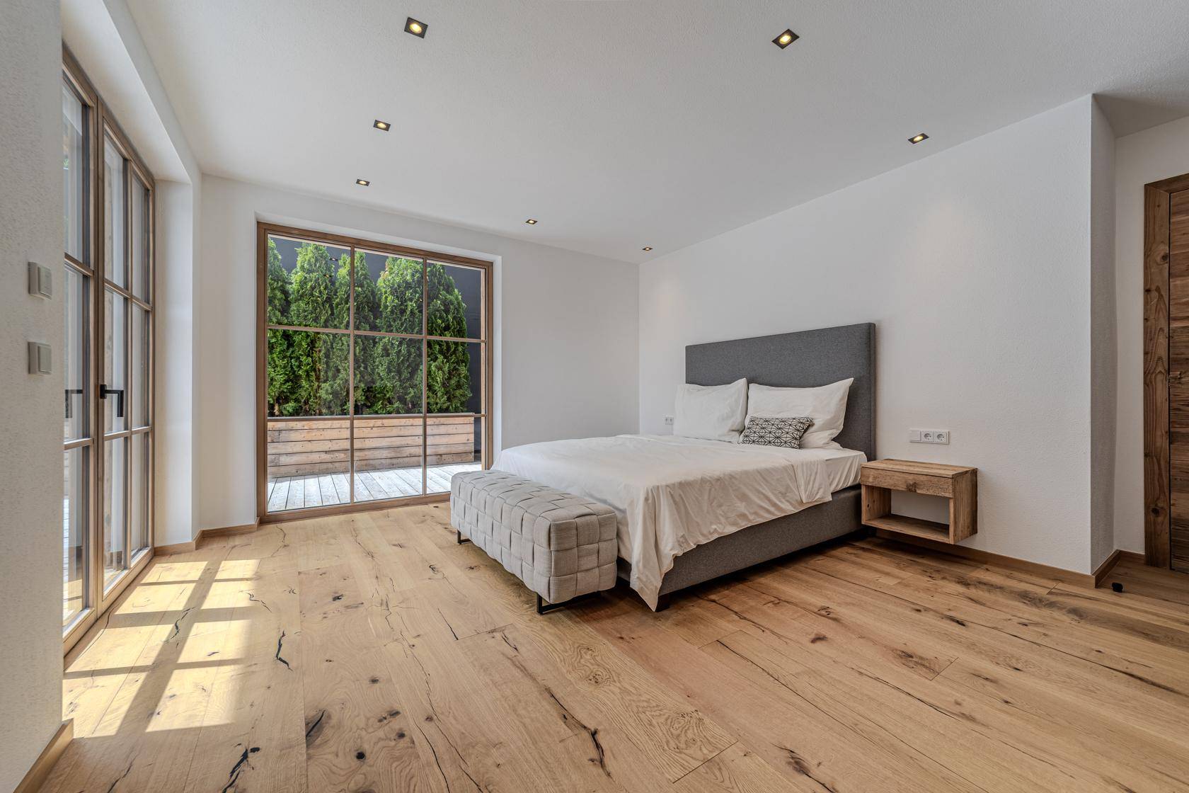 Geräumiges Schlafzimmer mit Holzboden, großem Fenster und viel natürlichem Licht.