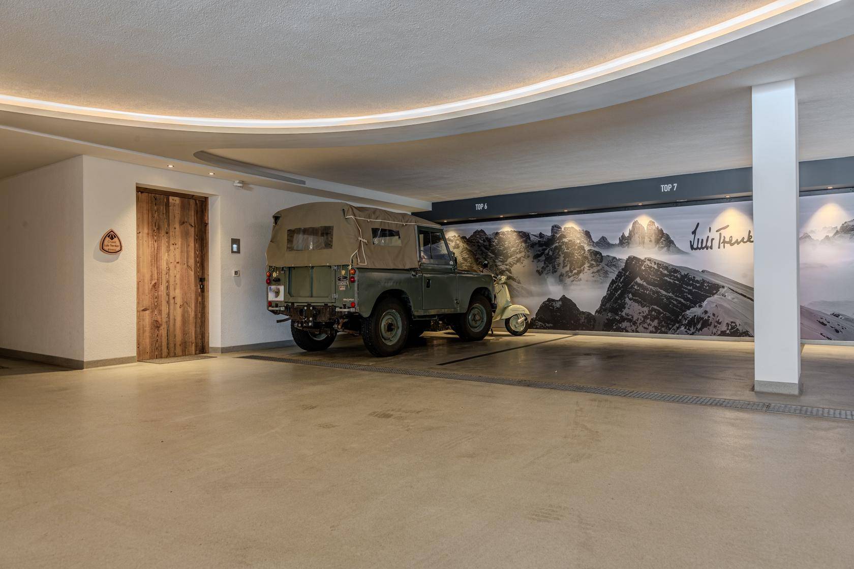 Geräumige Tiefgarage mit Betonboden und dekorativer Wandgestaltung, bietet Platz für Fahrzeuge.