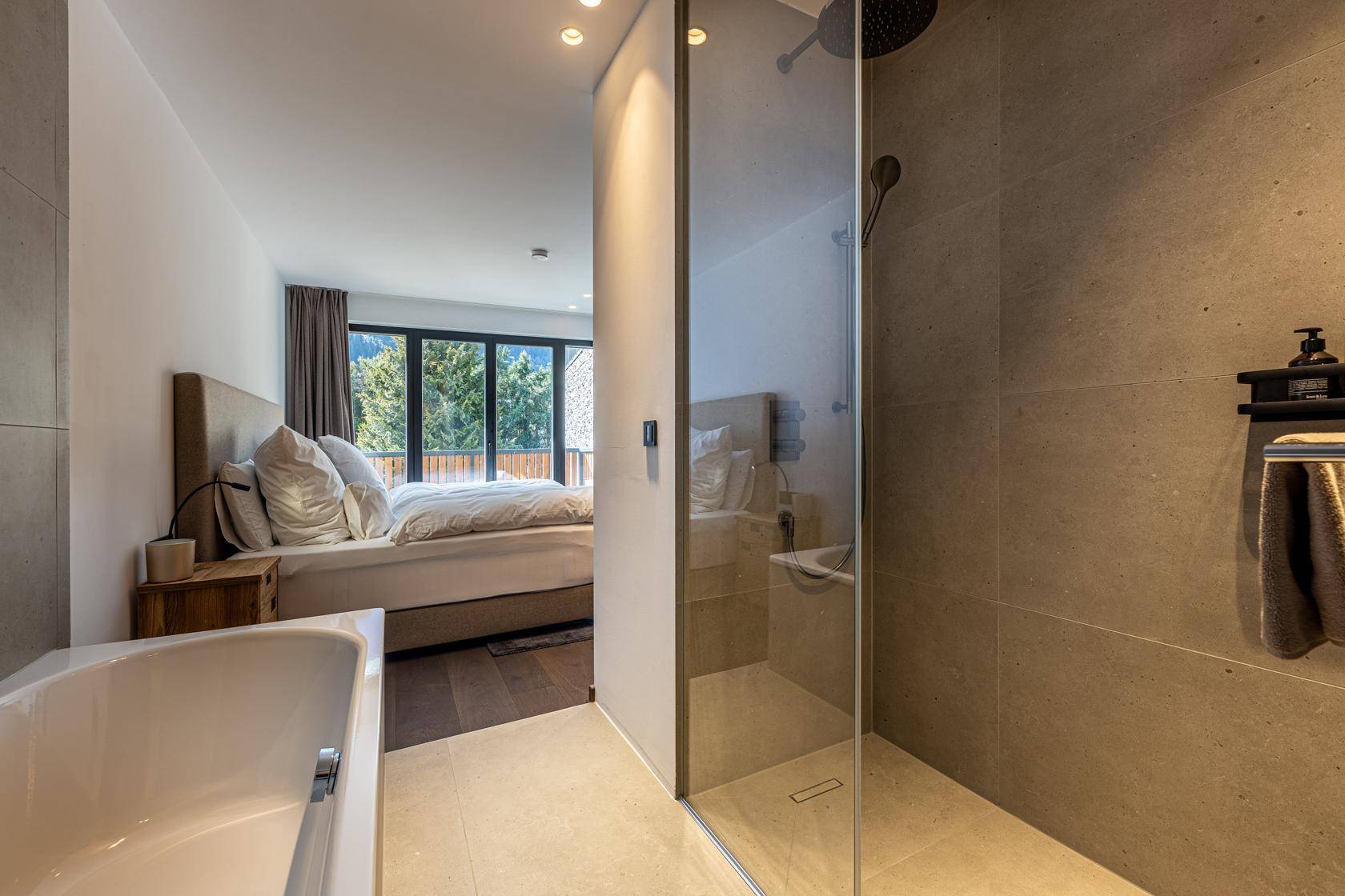 Modernes Badezimmer mit begehbarer Dusche, Badewanne und direktem Zugang zum Schlafzimmer.