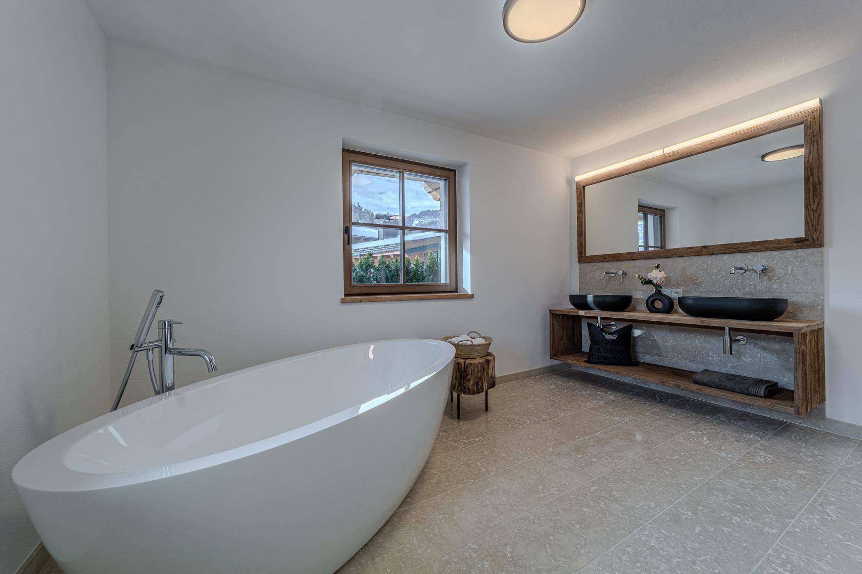 Modernes Badezimmer mit freistehender Badewanne, Doppelwaschbecken und Fenster.