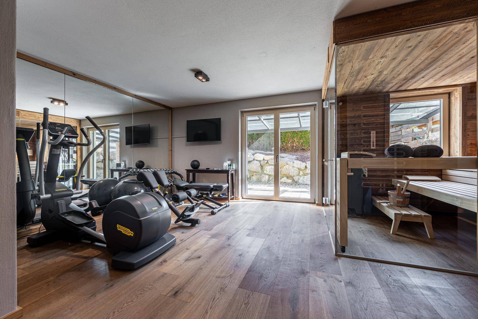 Fitnessraum mit verschiedenen Trainingsgeräten und direktem Zugang zur Sauna.
