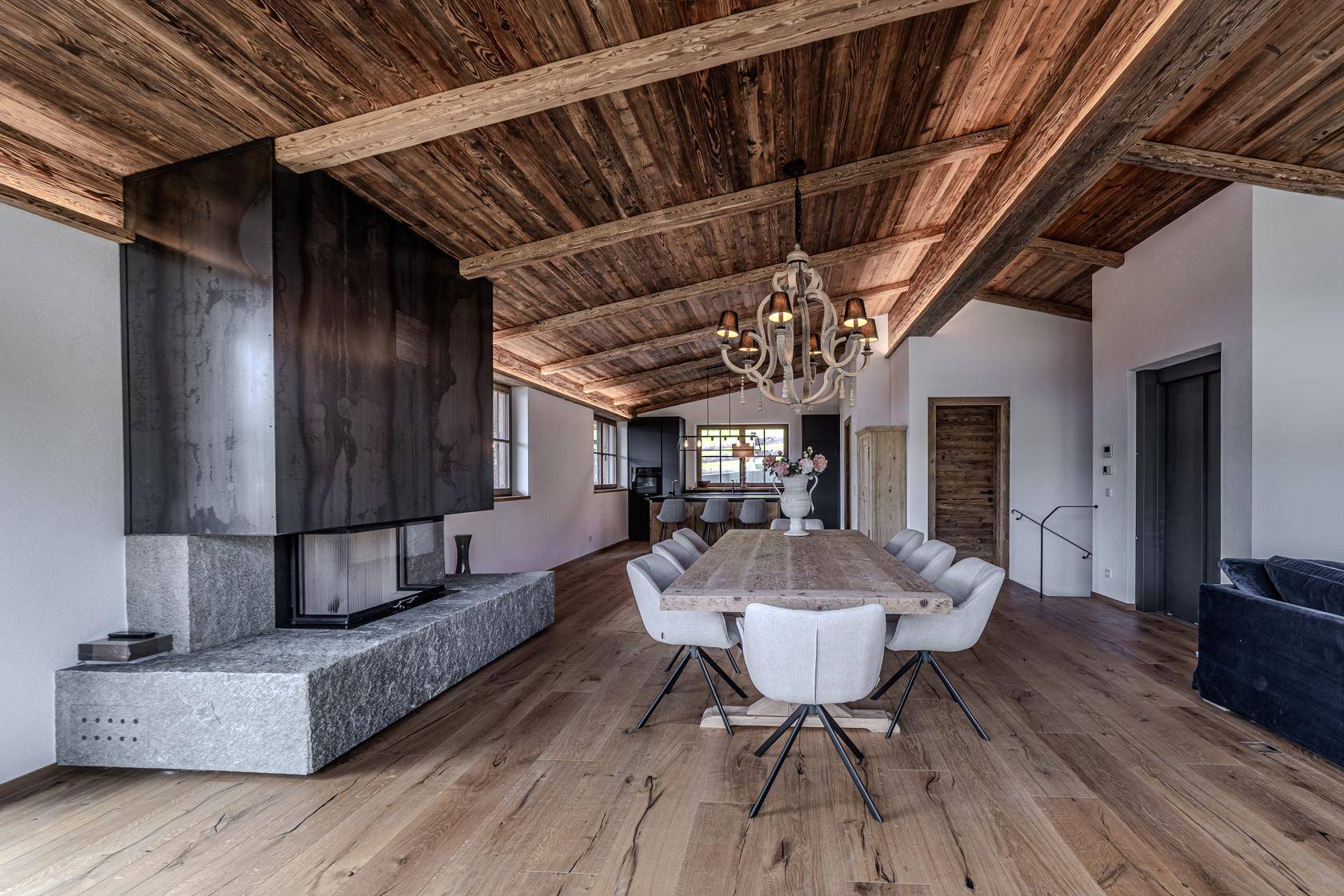 Heller Wohn-Essbereich mit Holzbalkendecke, elegantem Esstisch und integriertem Kamin.