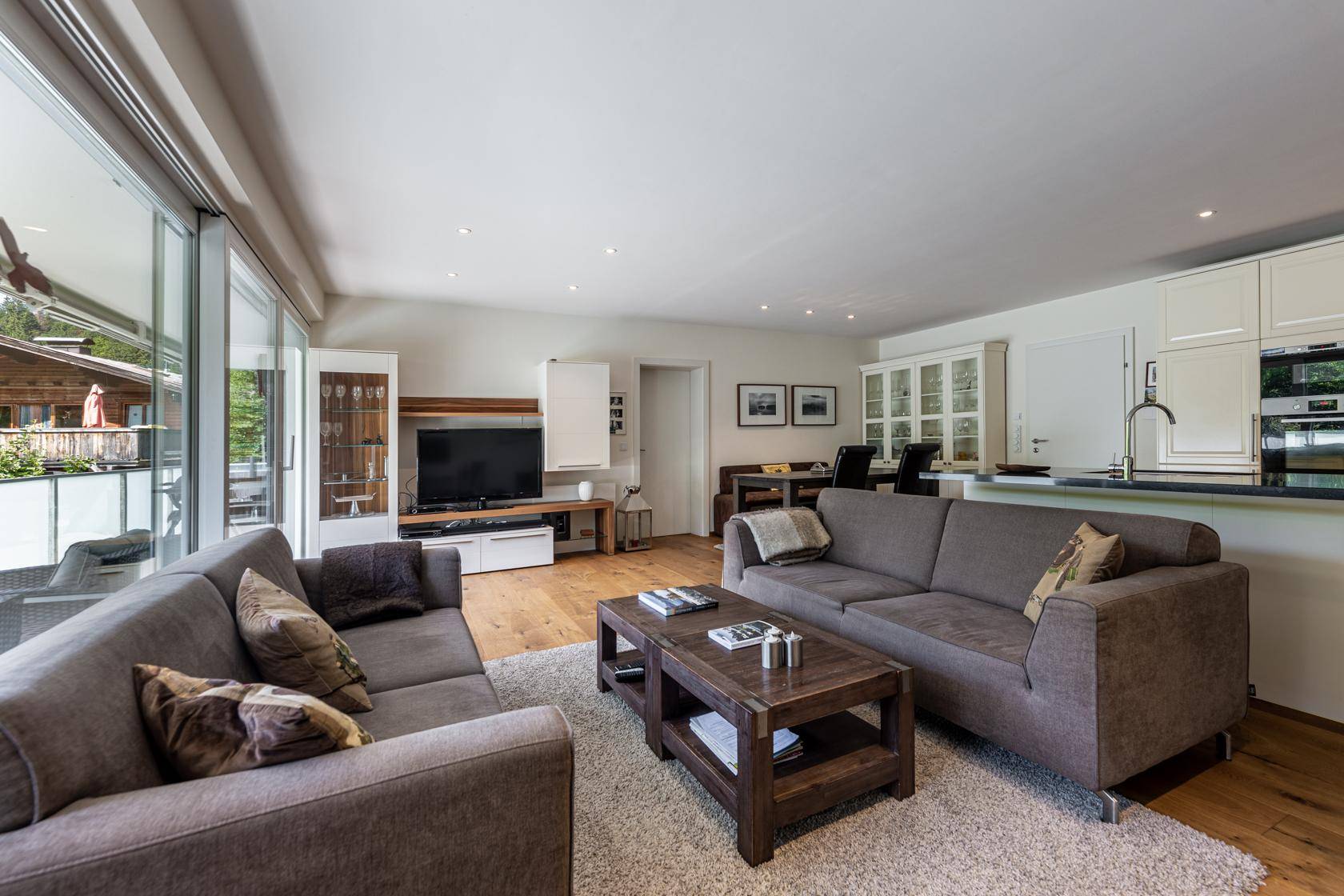 Geräumiger Wohnbereich mit Sofas, Esstisch und Zugang zu einem großen Balkon.