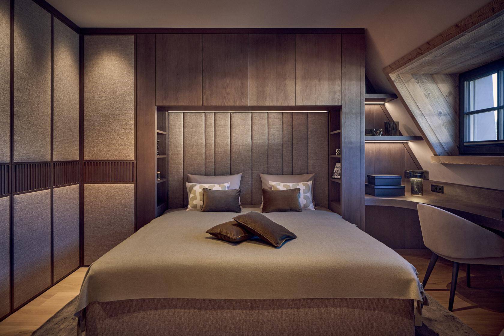Komfortables Schlafzimmer mit Holzwänden, Einbauschränken und einem integrierten Schreibtischbereich.