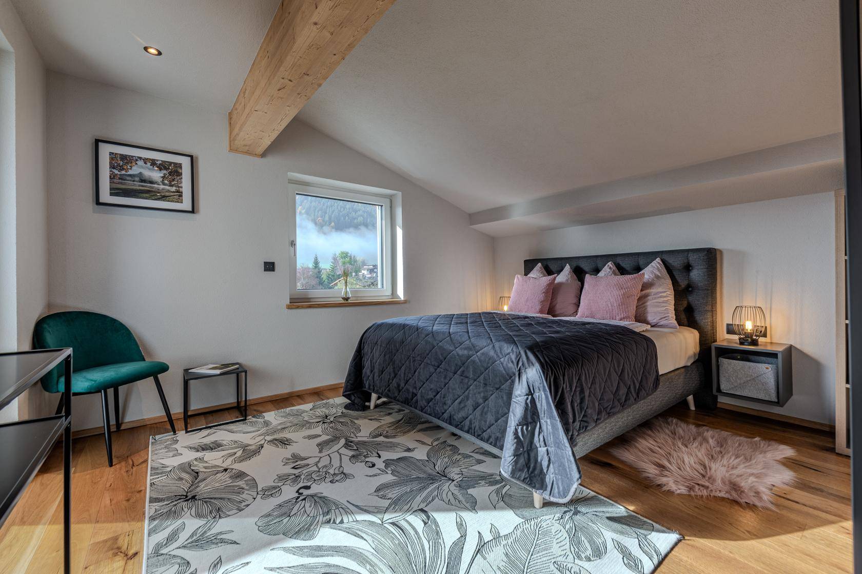 Ruhiges Schlafzimmer im Dachgeschoss mit Holzbalken, Fenster und gemütlicher Einrichtung.