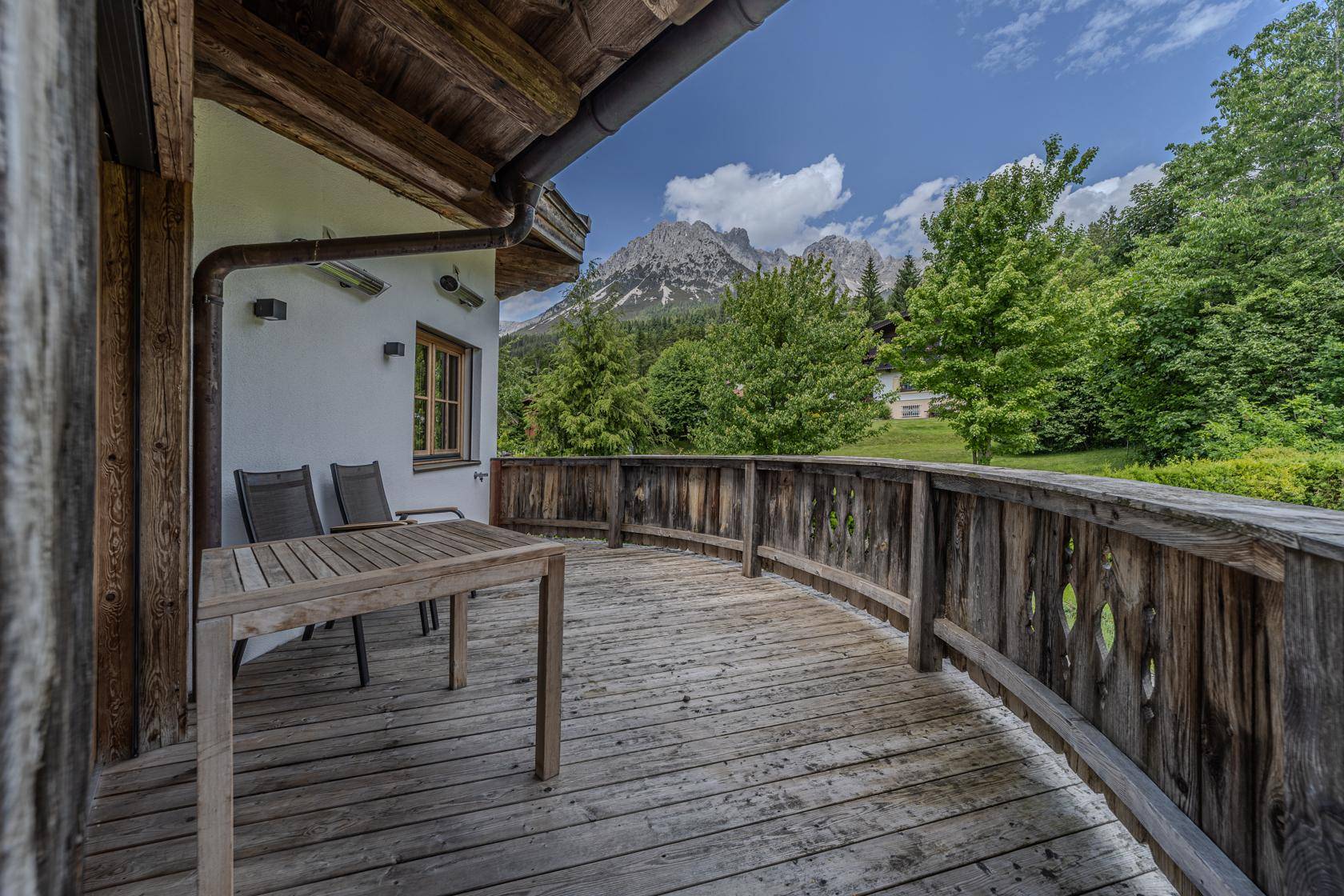 Geräumiger Holzbalkon mit Sitzgelegenheiten und beeindruckendem Bergblick.